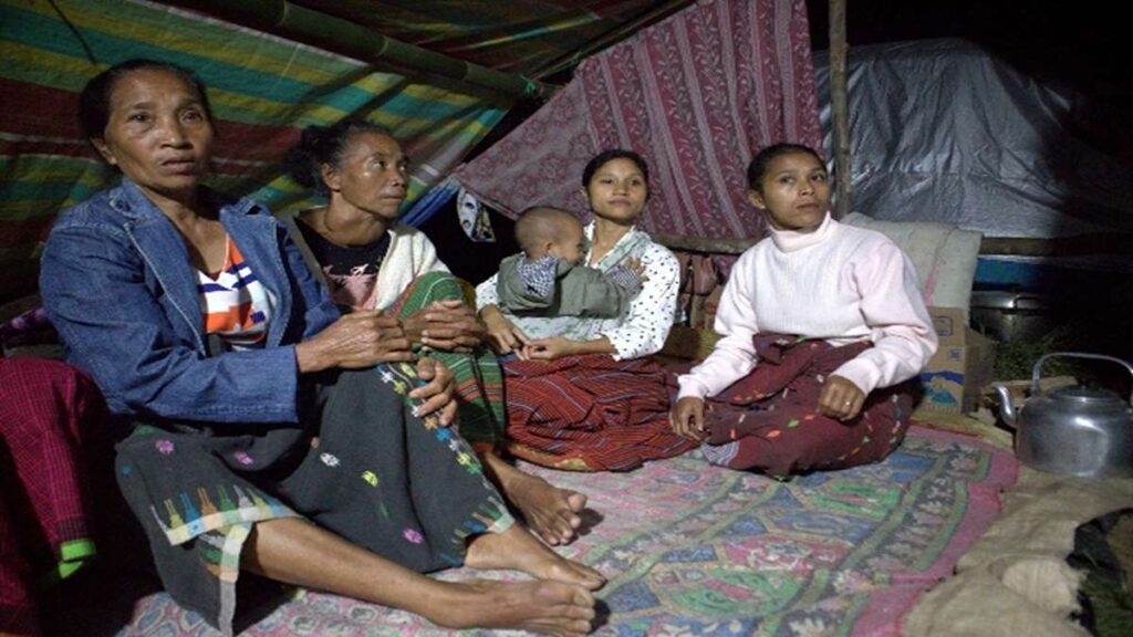 Posko Pengungsian NTT berduka akibat seorang balita meninggal dunia, Beberapa perempuan duduk bersama di dalam tenda beralaskan tikar, salah satunya menggendong anak kecil