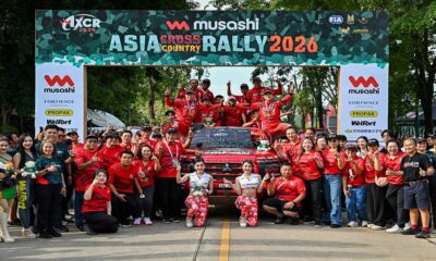 Duet Balap Komunitas Dunia se Asia, Tim reli Asia Cross Country Rally 2026 berpose bersama di depan mobil balap dan papan latar acara