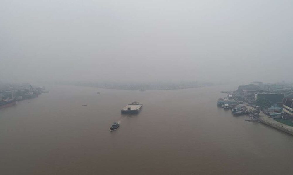 Kapal Sungai Kapuas Tak Berlayar Jarak Pandang Cuma 80 Meter, Kapal tongkang melintas di sungai yang diselimuti kabut tebal di bawah langit abu-abu