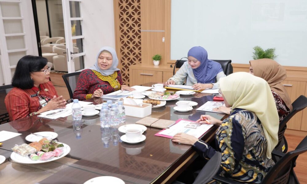 Beberapa perempuan sedang duduk mengelilingi meja rapat di ruang kantor