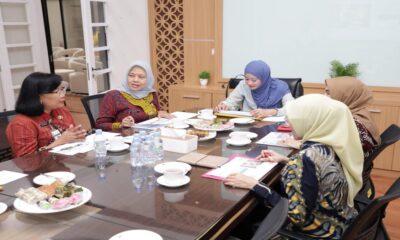 Beberapa perempuan sedang duduk mengelilingi meja rapat di ruang kantor