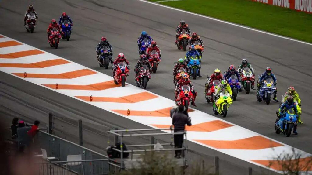 Kalender MotoGP 2026 Resmi Geser Sirkuit Eropa Siap Invasi Kota Besar 52 Kalender rilis, Sekelompok pembalap MotoGP memacu motor mereka di tikungan sirkuit dengan pembatas jalan merah putih