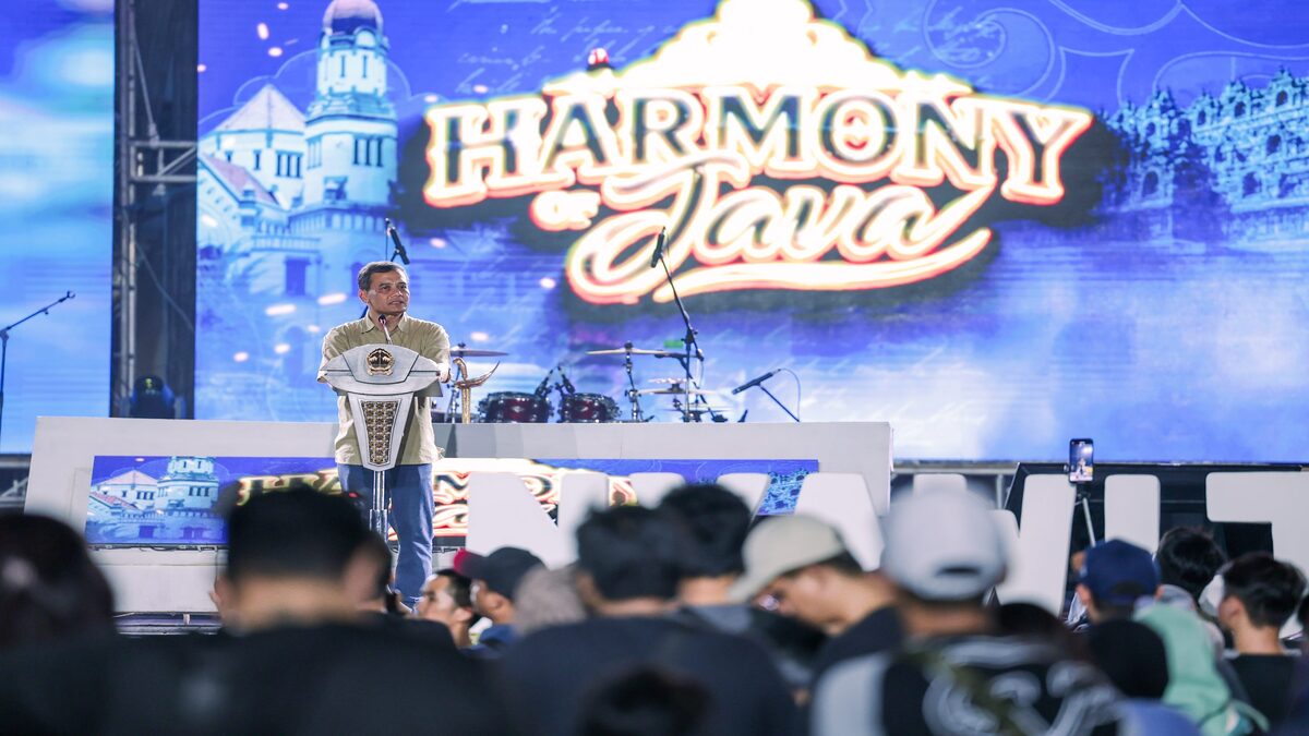 Spektakuler! Harmony of Java Hadirkan Panggung Nostalgia Warga Jateng 51 Seorang pria berdiri di atas panggung di depan layar bertuliskan Harmony of Java, berbicara di hadapan penonton yang memadati area