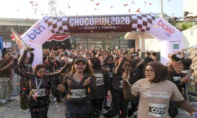 Chocorun 2026 Di kota Bogor Runner city, Para peserta lari Chocorun 2026 yang mengenakan pakaian olahraga cokelat tampak antusias melewati garis start di bawah konfeti yang berjatuhan