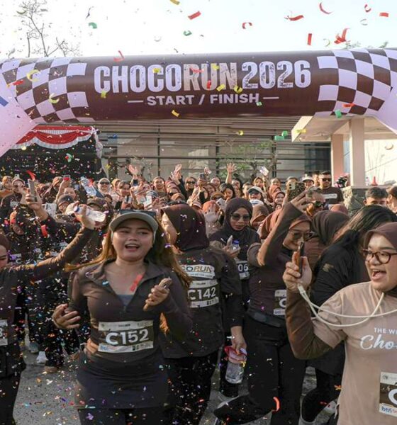 Chocorun 2026 Di kota Bogor Runner city, Para peserta lari Chocorun 2026 yang mengenakan pakaian olahraga cokelat tampak antusias melewati garis start di bawah konfeti yang berjatuhan