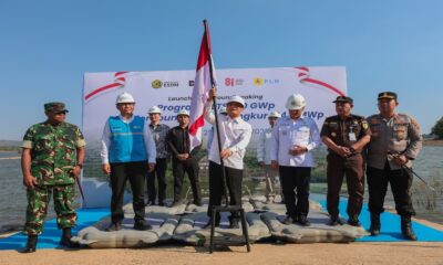 Menteri ESDM memegang tiang bendera Merah Putih dalam acara peluncuran dan peletakan batu pertama PLTS, didampingi pejabat dan aparat keamanan