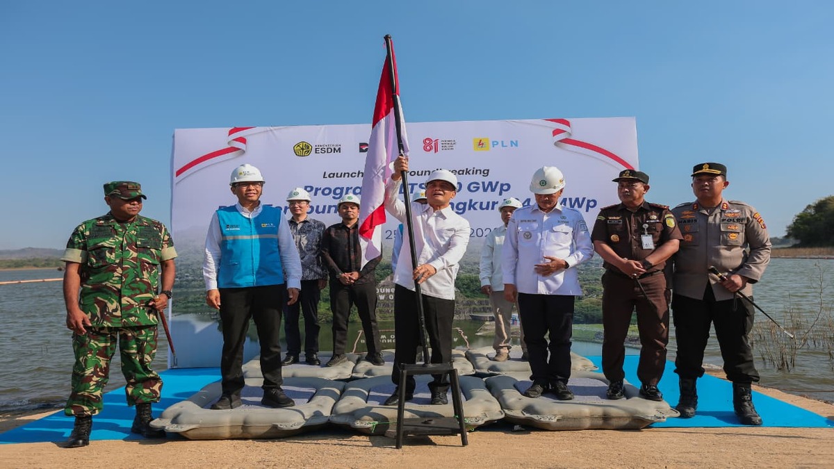 Menteri ESDM memegang tiang bendera Merah Putih dalam acara peluncuran dan peletakan batu pertama PLTS, didampingi pejabat dan aparat keamanan
