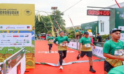 Para pelari memasuki garis finish pada ajang maraton dengan timer digital menunjukkan waktu 00:34:08