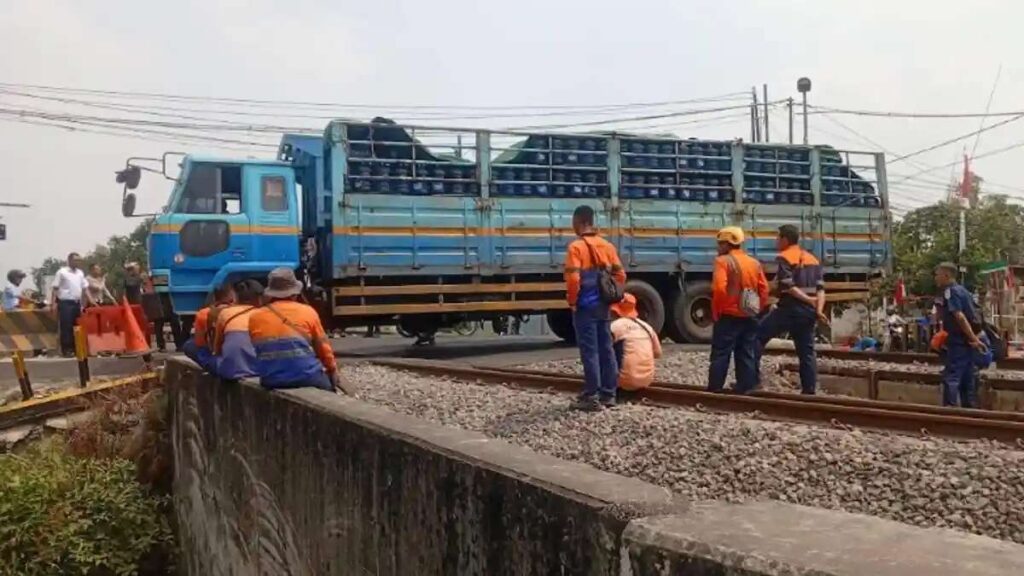 Perjalanan KA Madiun 4 Rute Resmi Terganggu Akibat Truk Mogok 52 Perjalanan KA terhambat, Truk muatan tabung gas terjebak di rel kereta api dengan petugas di sekitar lokasi