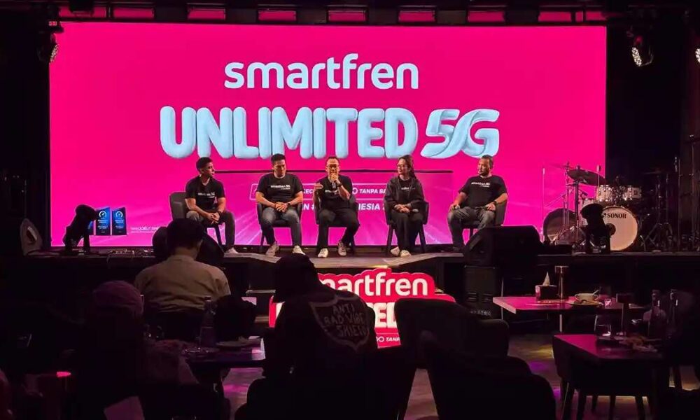 beberapa orang narasumber duduk di atas panggung dengan latar layar merah yang menampilkan tulisan jaringan internet Smartfren Unlimited 5G