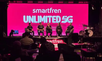 beberapa orang narasumber duduk di atas panggung dengan latar layar merah yang menampilkan tulisan jaringan internet Smartfren Unlimited 5G