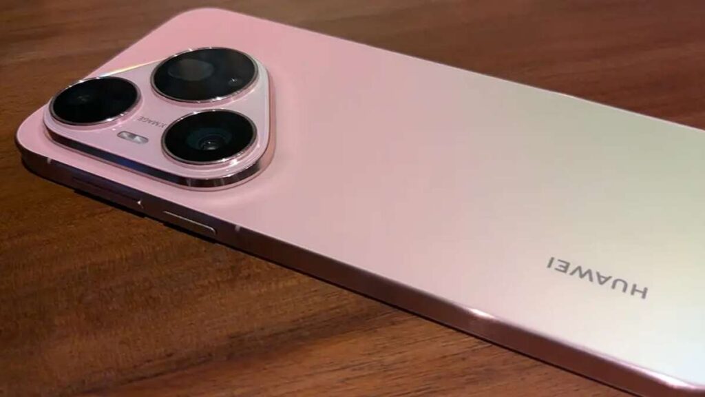 Segera Hadir, Huawei Pura90s Series 5G Bawa Kamera Telefoto 200MP dan Fitur AI Canggih 52 Sisi belakang ponsel Huawei berwarna merah muda dengan modul kamera segitiga menonjol di atas permukaan kayu
