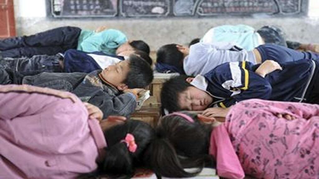 Anak-anak sekolah tidur siang di atas meja di dalam kelas