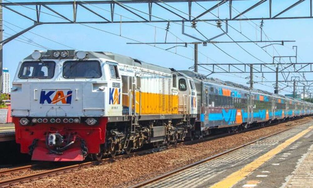 Kereta api jarak jauh KAI melintas di stasiun dengan lokomotif putih-kuning berlogo KAI dan rangkaian gerbong stainless steel