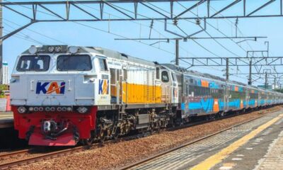 Kereta api jarak jauh KAI melintas di stasiun dengan lokomotif putih-kuning berlogo KAI dan rangkaian gerbong stainless steel