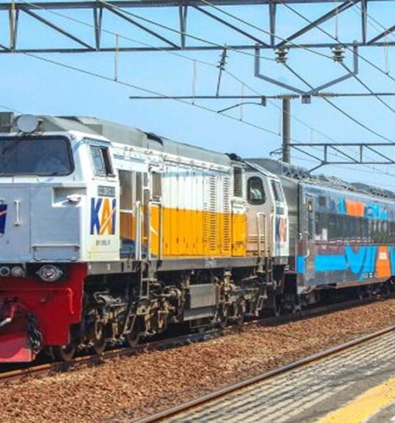 Kereta api jarak jauh KAI melintas di stasiun dengan lokomotif putih-kuning berlogo KAI dan rangkaian gerbong stainless steel