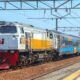 Kereta api jarak jauh KAI melintas di stasiun dengan lokomotif putih-kuning berlogo KAI dan rangkaian gerbong stainless steel