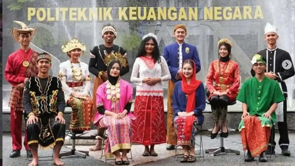 Sekelompok mahasiswa berpose mengenakan pakaian adat dari berbagai daerah di Indonesia dengan latar belakang tulisan Politeknik Keuangan Negara STAN