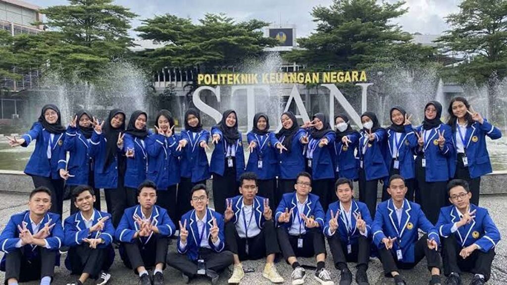 Sekelompok mahasiswa PKN STAN mengenakan almamater biru berpose bersama di depan air mancur