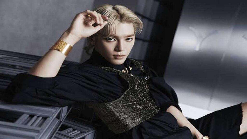 Taeyong Buka Suara Soal Mark Keluar dari NCT, Ungkap Alasan Sebenarnya 52 Taeyong mengenakan pakaian hitam dan aksesori emas, bersandar dengan tangan di kepala dalam pose bergaya