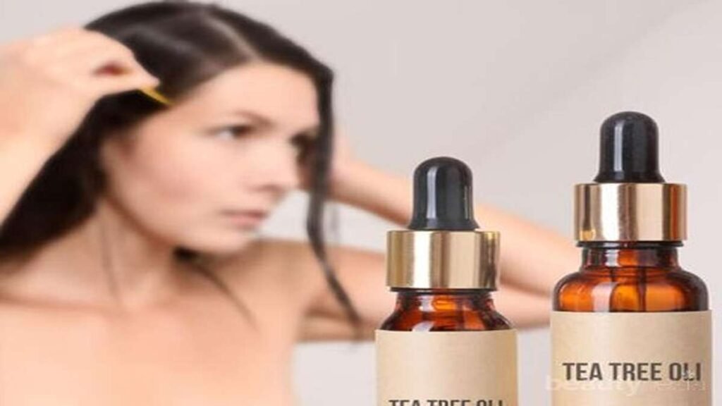 Seorang wanita sedang mengaplikasikan minyak tea tree pada rambutnya di dekat dua botol minyak tea tree