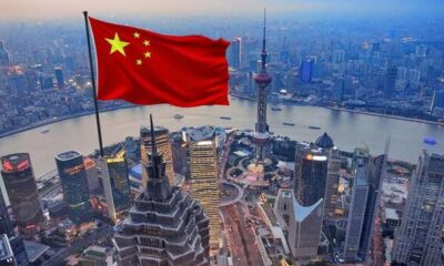 Bendera China berkibar di atas pemandangan cakrawala kota Shanghai dengan gedung-gedung pencakar langit dan sungai