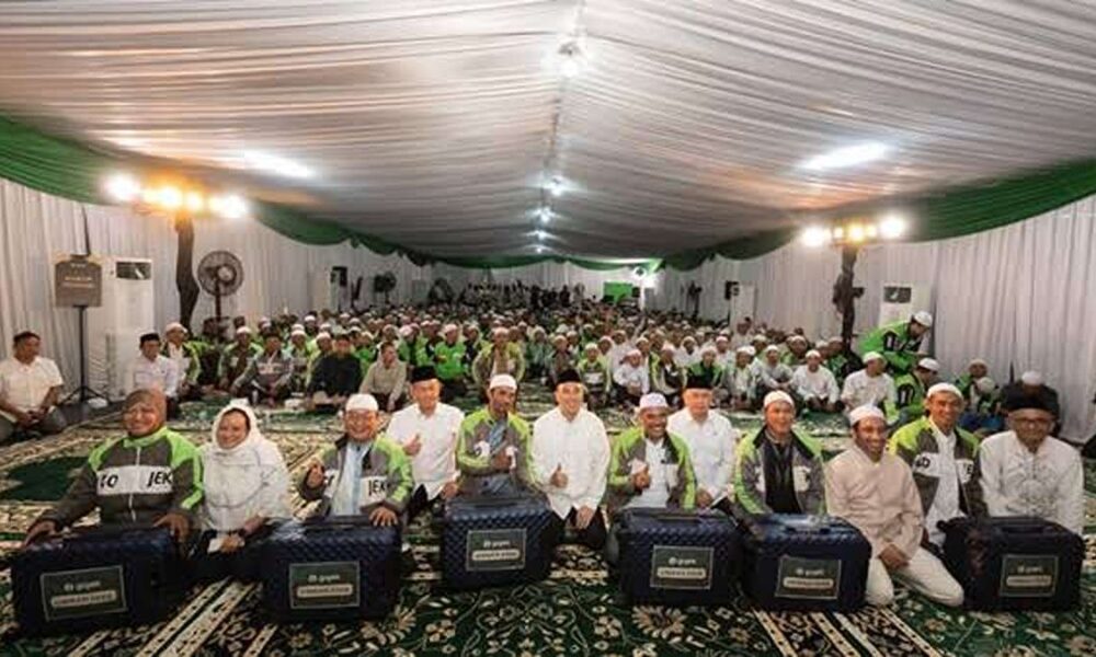 Suasana acara kebersamaan dan pembagian bantuan di dalam tenda besar yang dihadiri banyak peserta dan pengemudi ojek online