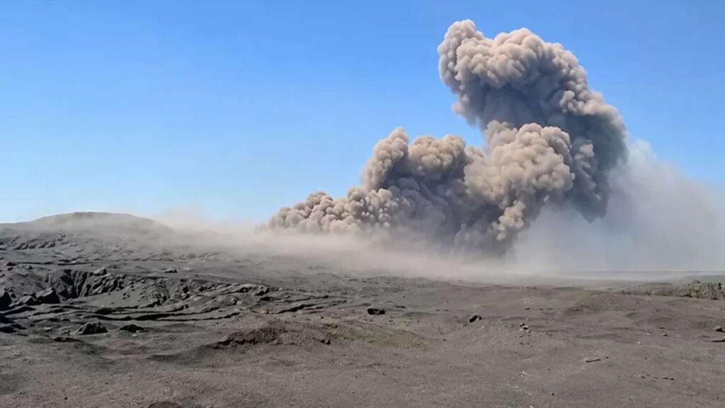 Anak krakatau dalam mode siaga, Asap tebal dan abu vulkanik membubung ke udara di atas lanskap berpasir akibat letusan gunung berapi