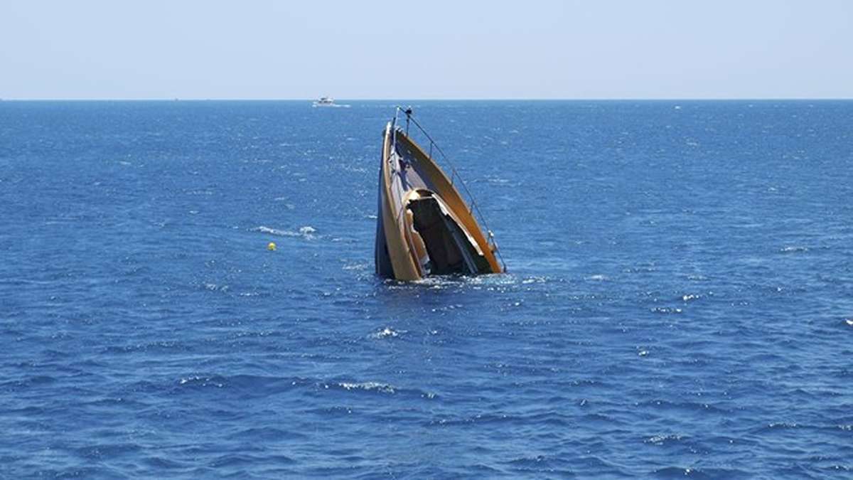 Kecelakaan Kapal Feri di Zimbabwe Sebuah kapal pesiar tenggelam secara vertikal di tengah laut yang biru, dengan bagian haluan mengarah ke atas