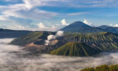 Pemandangan lanskap Gunung Bromo berselimut kabut dengan latar pegunungan dan langit berawan