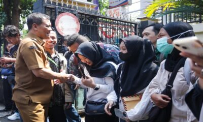 Seorang pejabat berseragam khaki menyalami warga di antara kerumunan
