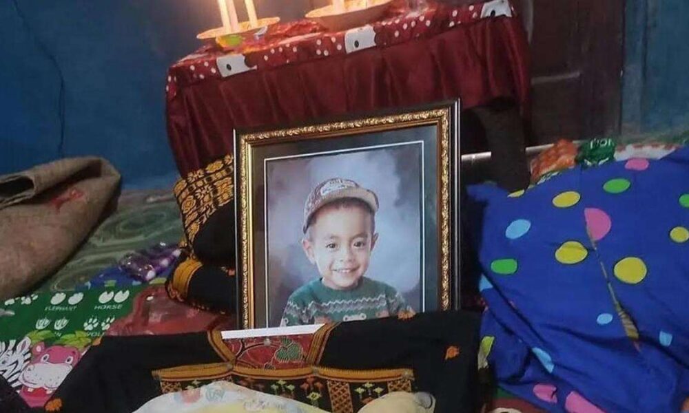 Posko Pengungsian NTT berduka akibat seorang balita meninggal dunia, Foto berbingkai seorang anak laki-laki yang tersenyum mengenakan topi dan sweter hijau, diletakkan di ruangan dengan latar belakang meja beralkas merah