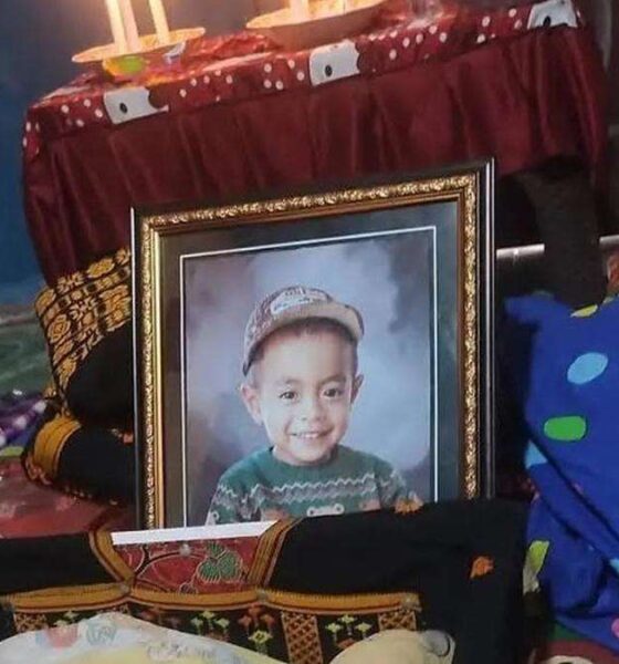 Posko Pengungsian NTT berduka akibat seorang balita meninggal dunia, Foto berbingkai seorang anak laki-laki yang tersenyum mengenakan topi dan sweter hijau, diletakkan di ruangan dengan latar belakang meja beralkas merah