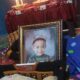 Pengungsian NTT Berduka Mencekam Balita 2 Tahun Meninggal Dunia 55 Posko Pengungsian NTT berduka akibat seorang balita meninggal dunia, Foto berbingkai seorang anak laki-laki yang tersenyum mengenakan topi dan sweter hijau, diletakkan di ruangan dengan latar belakang meja beralkas merah