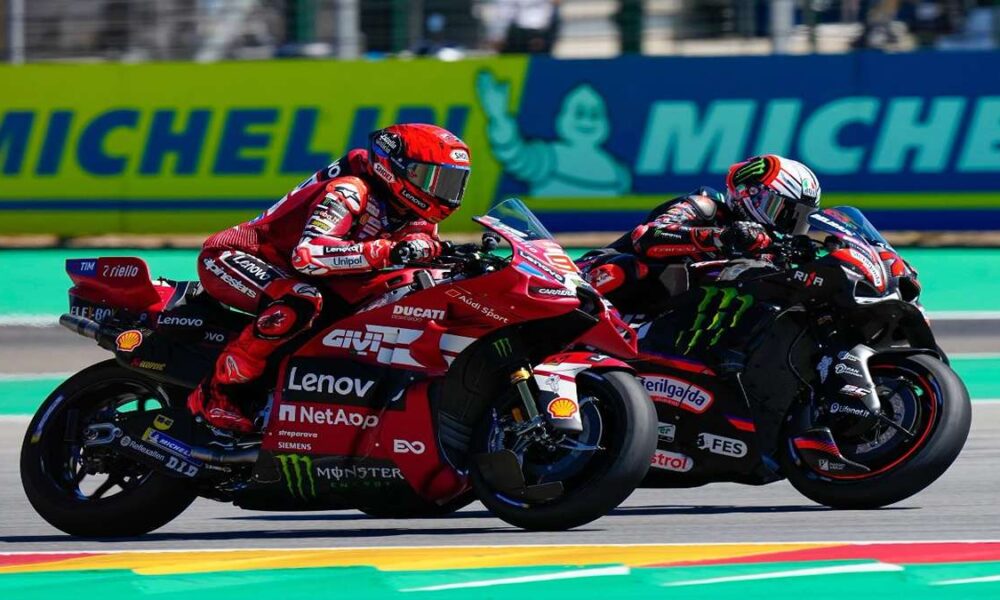 Duel Panas MotoGP Aragon Marquez Kalahkan Bezzecchi 300 KPJ, Dua pembalap MotoGP bersaing ketat di tikungan sirkuit dengan latar belakang papan sponsor Michelin