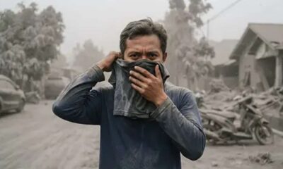 Seorang pria menutupi hidung dan mulutnya dengan kain di tengah lingkungan yang tertutup abu vulkanik