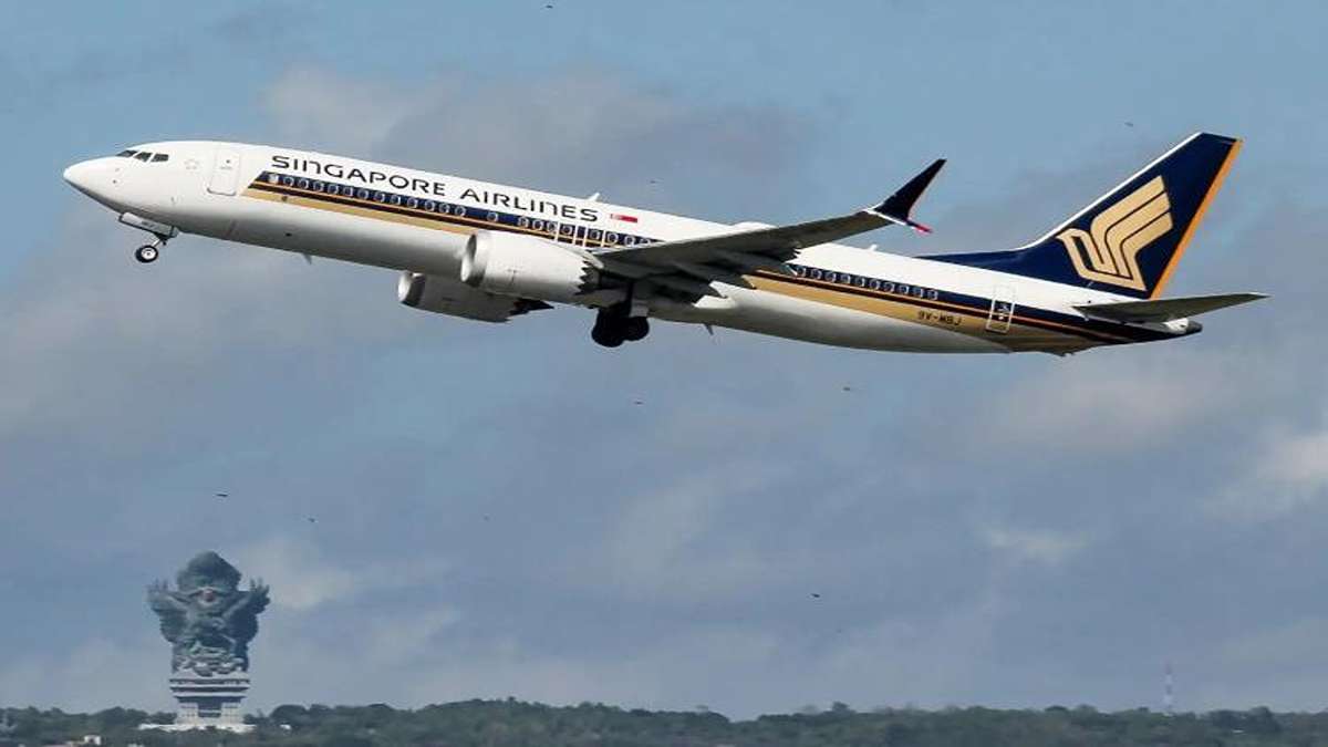 Pesawat Singapore Airlines lepas landas dengan latar belakang patung Garuda Wisnu Kencana di Bali