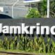 Fantastis! Laba Jamkrindo Semester I 2026 Meroket Tajam Hingga Rp 743 Miliar 54 Papan nama perusahaan Jamkrindo berwarna putih dengan latar belakang dinding abu-abu dan tanaman hias di depannya