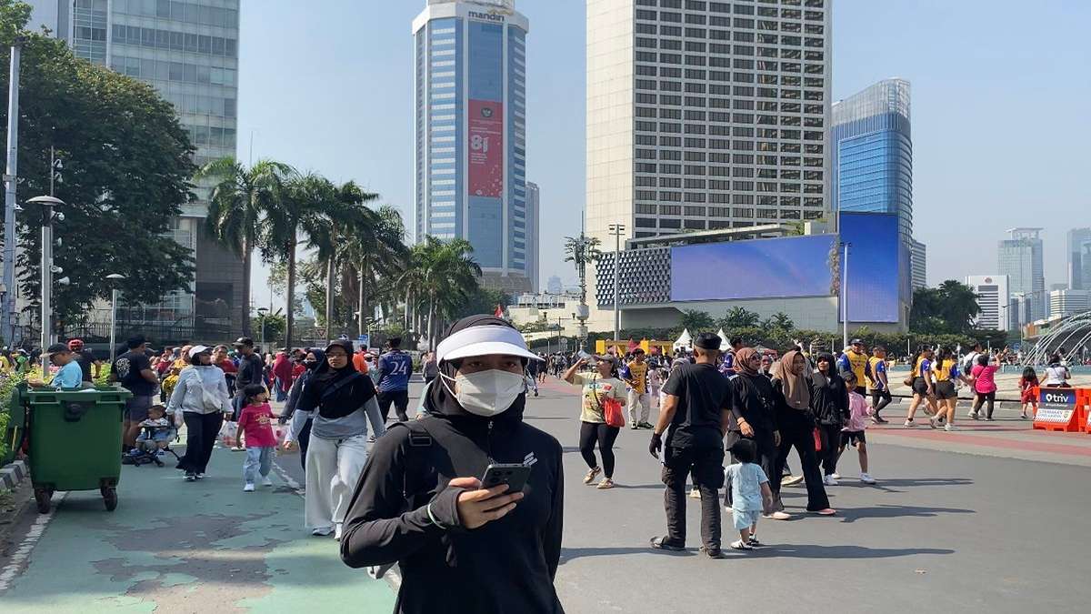 Suasana Hari Bebas Kendaraan Bermotor atau car free day di jalanan Jakarta yang ramai dengan pejalan kaki dan latar belakang gedung-gedung tinggi