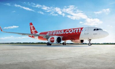 Pesawat komersial AirAsia terparkir di landasan di bawah langit biru berawan