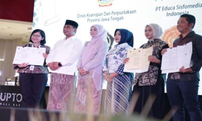 Enam orang berdiri di atas panggung menunjukkan dokumen kerja sama antara Dinas Kearsipan dan Perpustakaan Provinsi Jawa Tengah dengan PT Educa Sisfomedia Indonesia