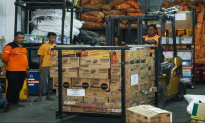 Petugas gudang menyiapkan kardus bantuan logistik dengan menggunakan forklift di dalam gudang