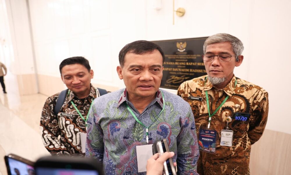 Tiga orang pria mengenakan kemeja batik dan tanda pengenal, berdiri berdampingan saat wawancara