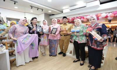 Sekelompok pejabat dan warga memegang berbagai produk kerajinan tangan lokal di dalam toko