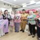 Sekelompok pejabat dan warga memegang berbagai produk kerajinan tangan lokal di dalam toko