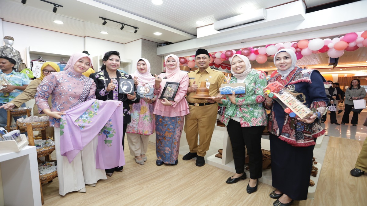 Sekelompok pejabat dan warga memegang berbagai produk kerajinan tangan lokal di dalam toko