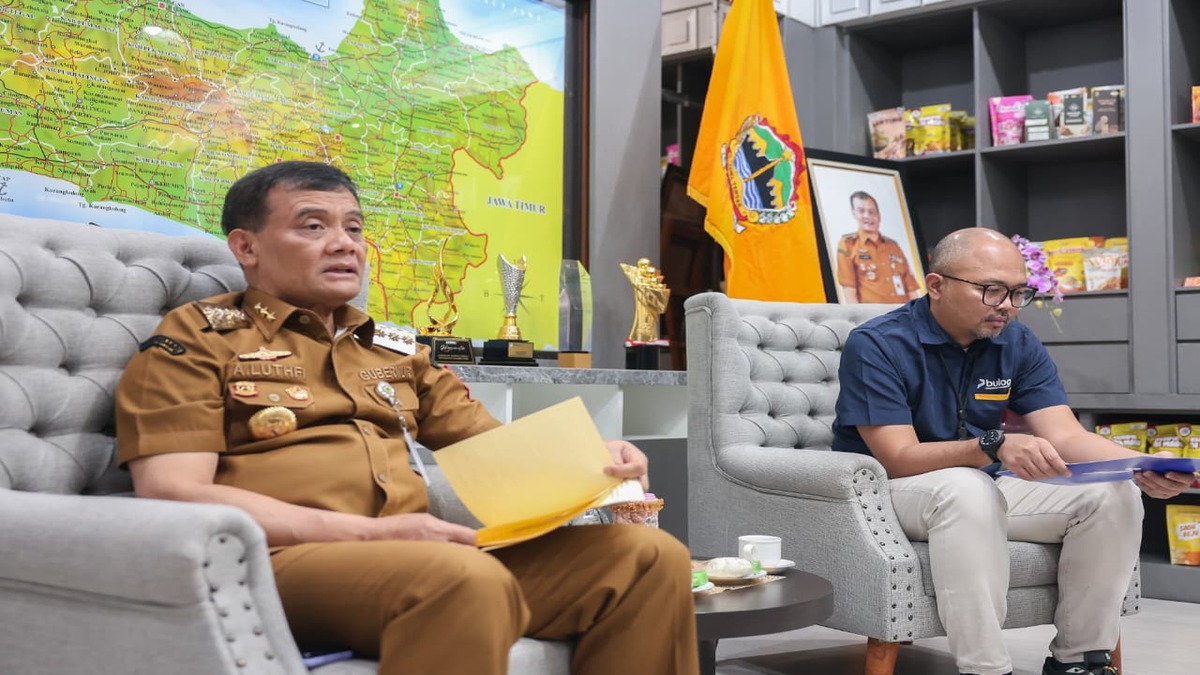 Waspada! Harga Beras Naik, Luthfi Instruksikan Intervensi Pasar 51 Dua orang pria sedang duduk di sofa sambil memegang dokumen di ruangan berlatar belakang peta dan rak pajangan