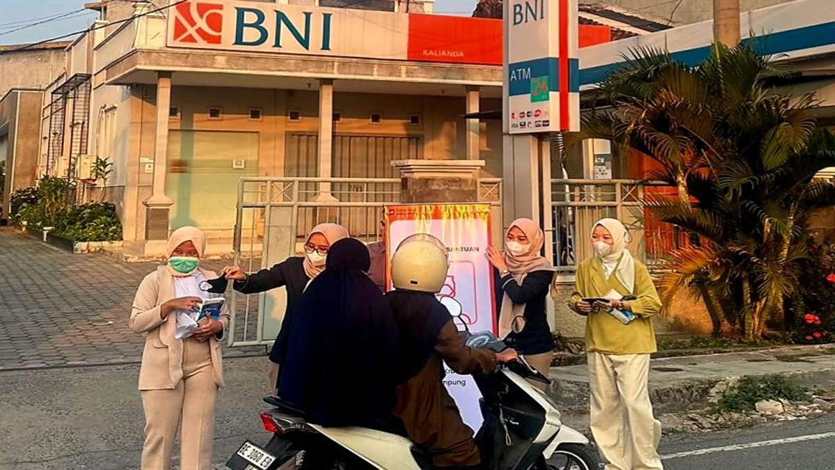 Beberapa wanita bermasker membagikan brosur kepada pengendara motor di depan gedung bank BNI