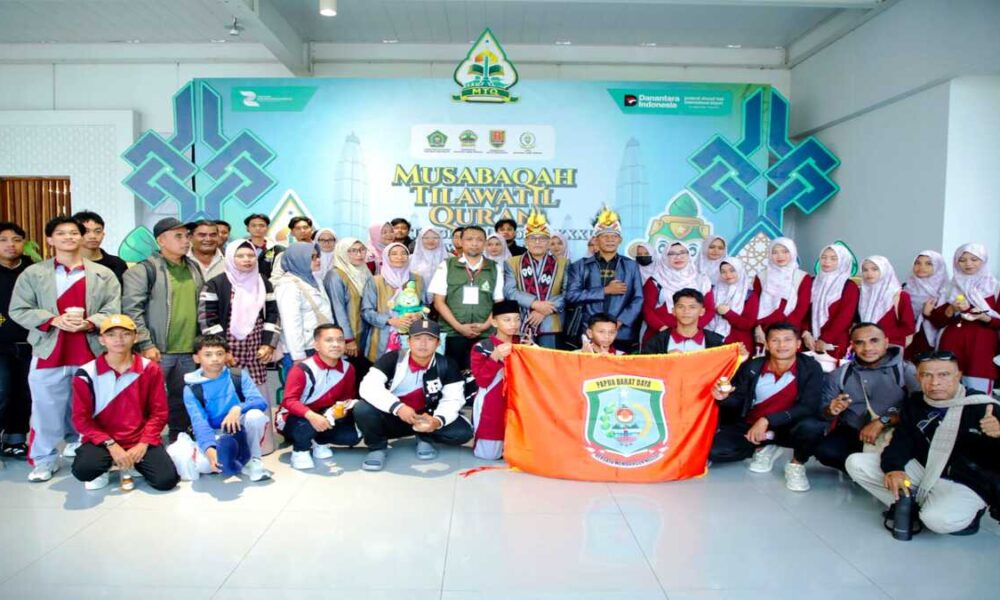 Kontingen Papua Barat Daya berfoto bersama dengan latar belakang spanduk Musabaqah Tilawatil Quran dan memegang bendera kontingen