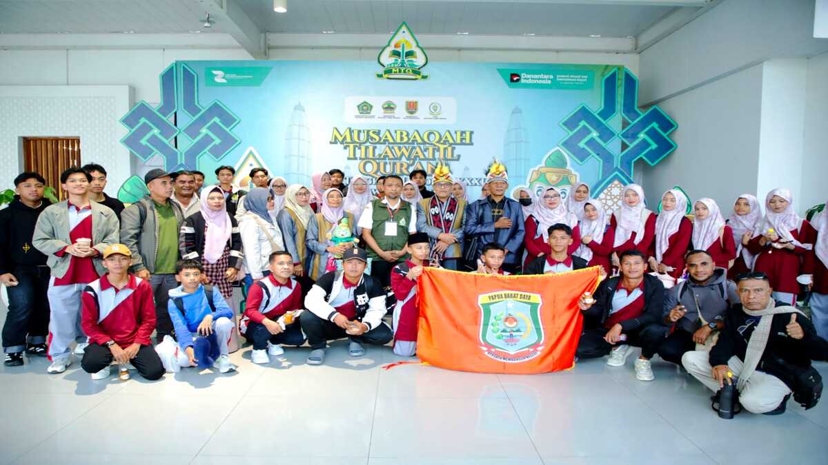 Kontingen Papua Barat Daya berfoto bersama dengan latar belakang spanduk Musabaqah Tilawatil Quran dan memegang bendera kontingen